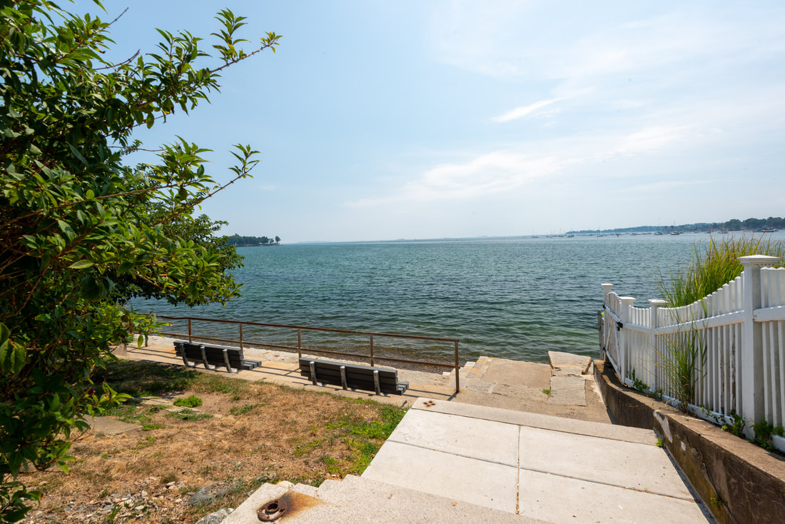 Photo of the public way across the street, showcasing two benches and an abundant view of the expansive ocean.